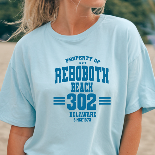 Person wearing a light blue t-shirt with 'Property of Rehoboth Beach 302 Delaware Since 1873' text.