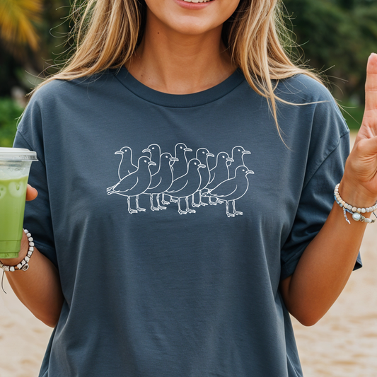 Person wearing a navy blue t-shirt with white duck design, holding a green drink.