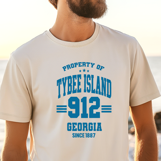 Person wearing a t-shirt with 'Property of Tybee Island 912 Georgia Since 1887' text on a beach.