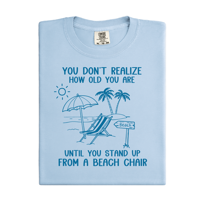 Light blue t-shirt with beach graphic and text on a white background