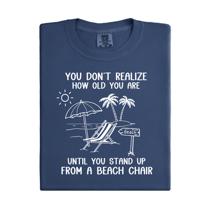 Folded navy blue t-shirt with beach-themed graphic and text on a white background