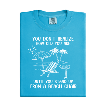 Blue t-shirt with beach-themed graphic and text on a white background