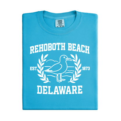 Folded blue sapphire t-shirt with white 'Rehoboth Beach Delaware' design on a white background