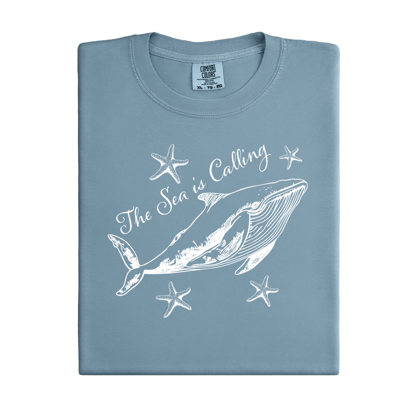 Comfort Colors t-shirt featuring a blue whale illustration surrounded by starfish and the handwritten-style text “The Sea is Calling.” The detailed marine artwork creates a calming coastal aesthetic. This unisex garment-dyed tee offers a soft vintage feel and relaxed fit, perfect for ocean lovers, beach trips, and anyone who enjoys sea-themed graphic shirts with a coastal vibe.