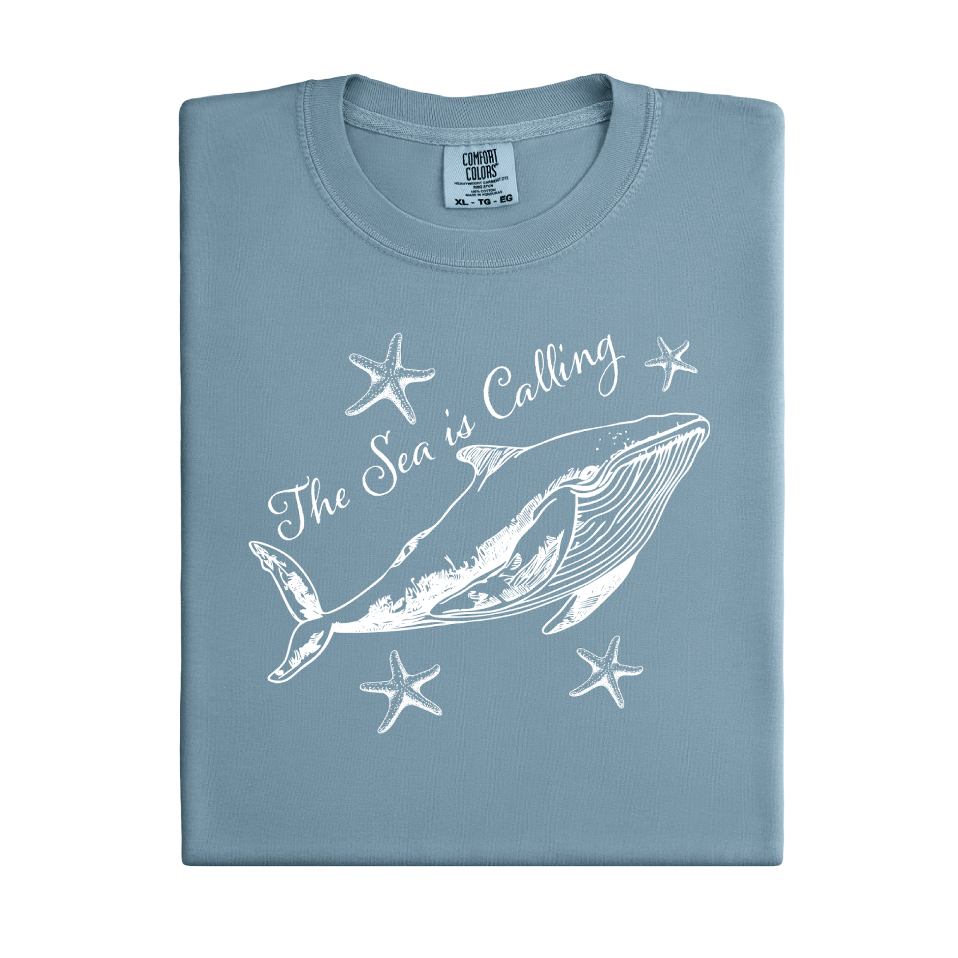 Comfort Colors t-shirt featuring a blue whale illustration surrounded by starfish and the handwritten-style text “The Sea is Calling.” The detailed marine artwork creates a calming coastal aesthetic. This unisex garment-dyed tee offers a soft vintage feel and relaxed fit, perfect for ocean lovers, beach trips, and anyone who enjoys sea-themed graphic shirts with a coastal vibe.