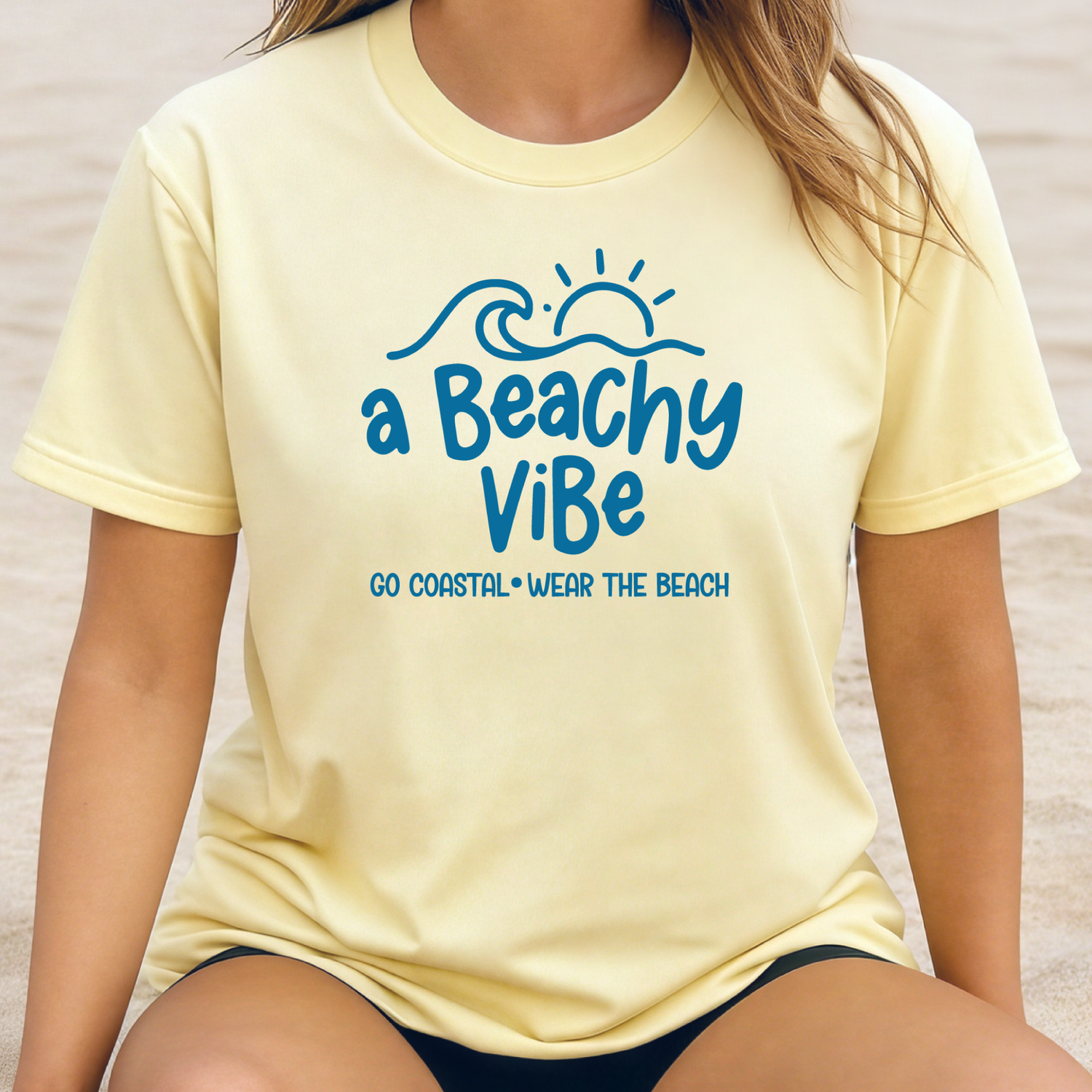 Person wearing a yellow t-shirt with 'a Beachy Vibe' text on a beach.