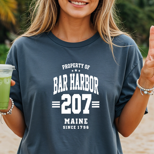 Person wearing a 'Property of Bar Harbor 207 Maine Since 1796' t-shirt on a beach.