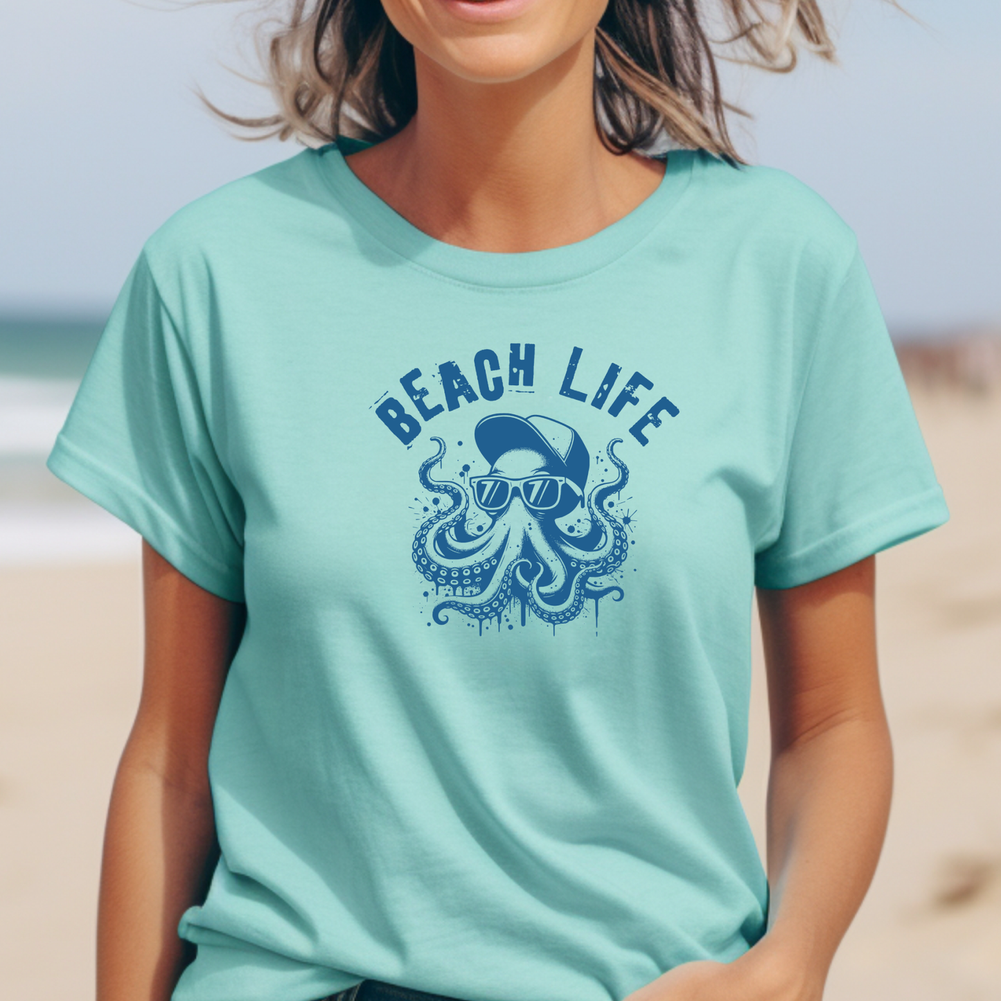 Comfort Colors 1717 "Beach Life" t shirt with a octopus with a baseball cap and sunglasses in a one color graphic. Picture of a girl  standing on the beach wearing a t shirt.