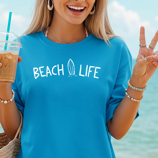 Woman wearing a sapphire blue 'Beach Life' t-shirt by the ocean.