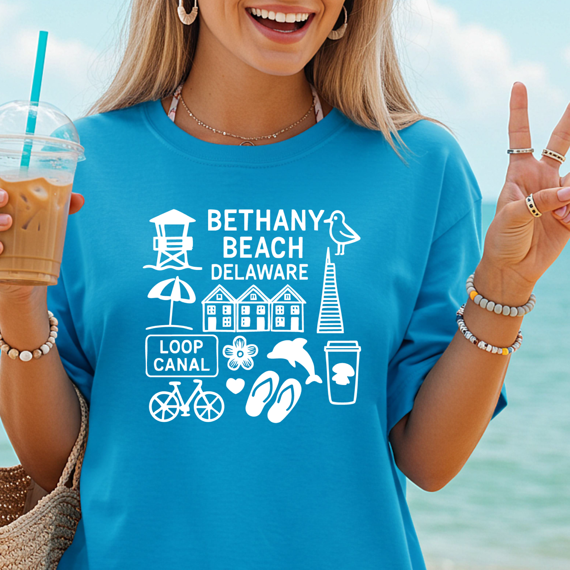 Woman wearing a blue t-shirt with Bethany Beach, Delaware graphics and text, holding a drink.