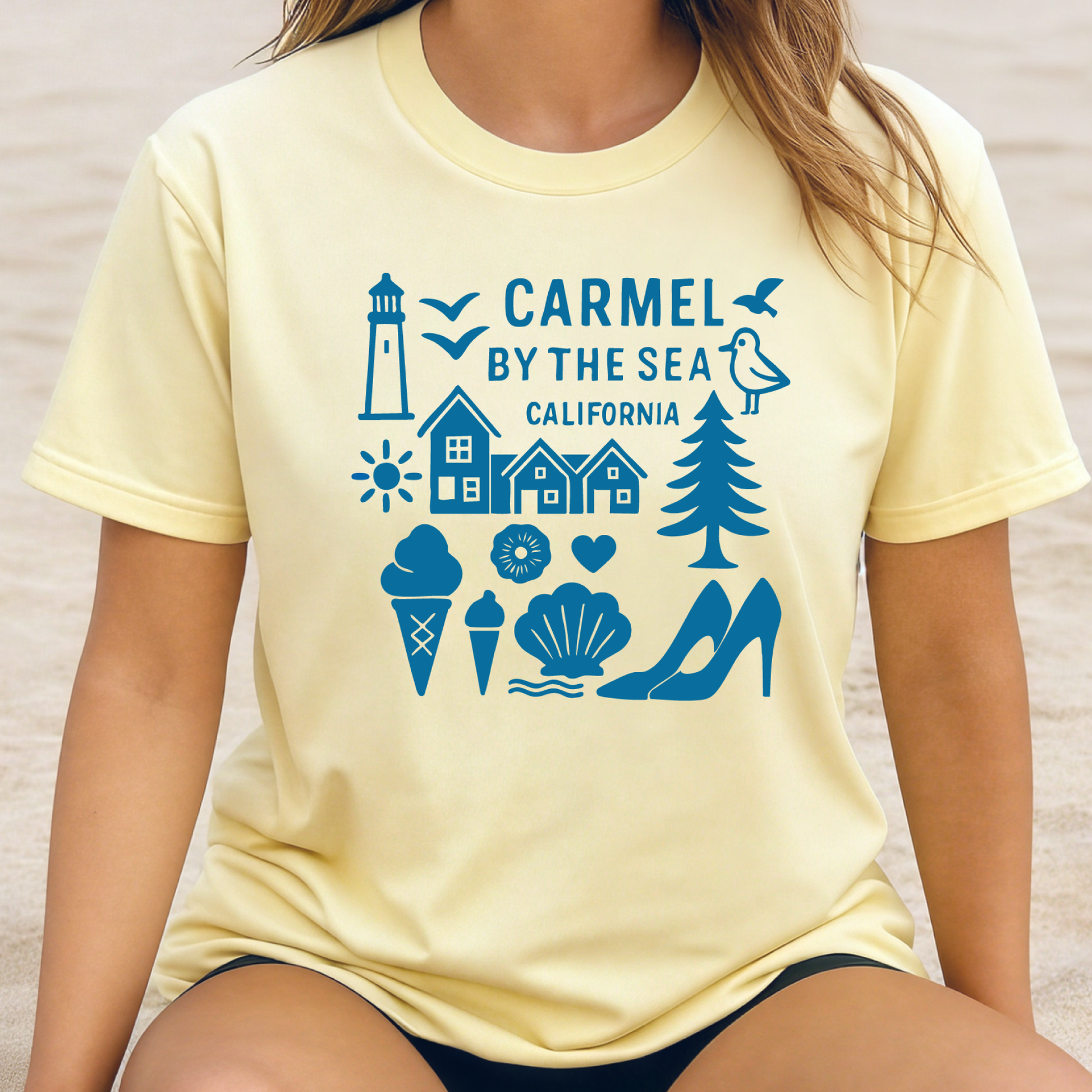 Person wearing a yellow t-shirt with blue graphics and text 'Carmel by the Sea, California' on a neutral background.