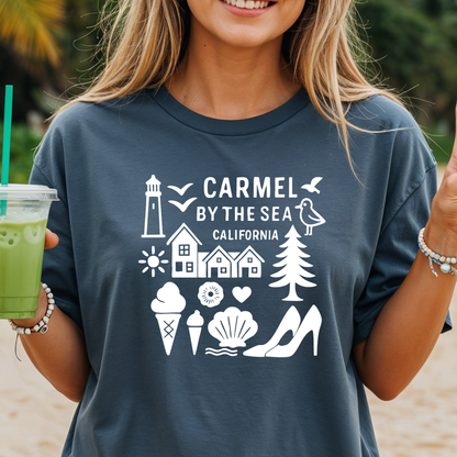 Person wearing a t-shirt with 'Carmel by the Sea, California' design on a beach.