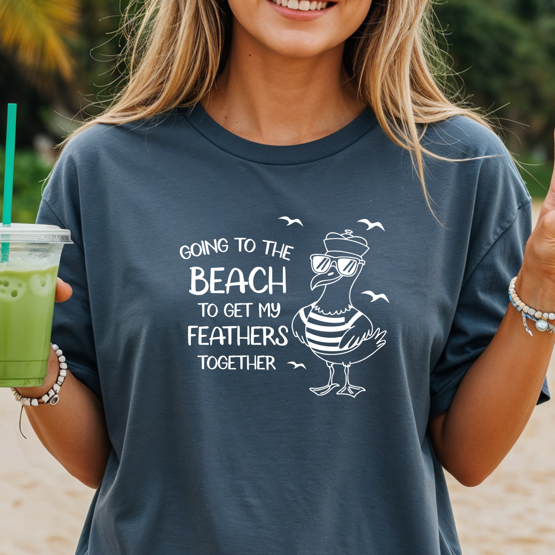 Comfort Colors t-shirt featuring a humorous blue seagull graphic wearing sunglasses and a striped shirt, beside the text “Going to the Beach to Get My Feathers Together.” Several flying birds surround the design, adding a fun coastal feel. This unisex garment-dyed tee offers a soft, vintage texture and relaxed fit, perfect for beach lovers, ocean fans, and anyone who enjoys playful summer graphic shirts.