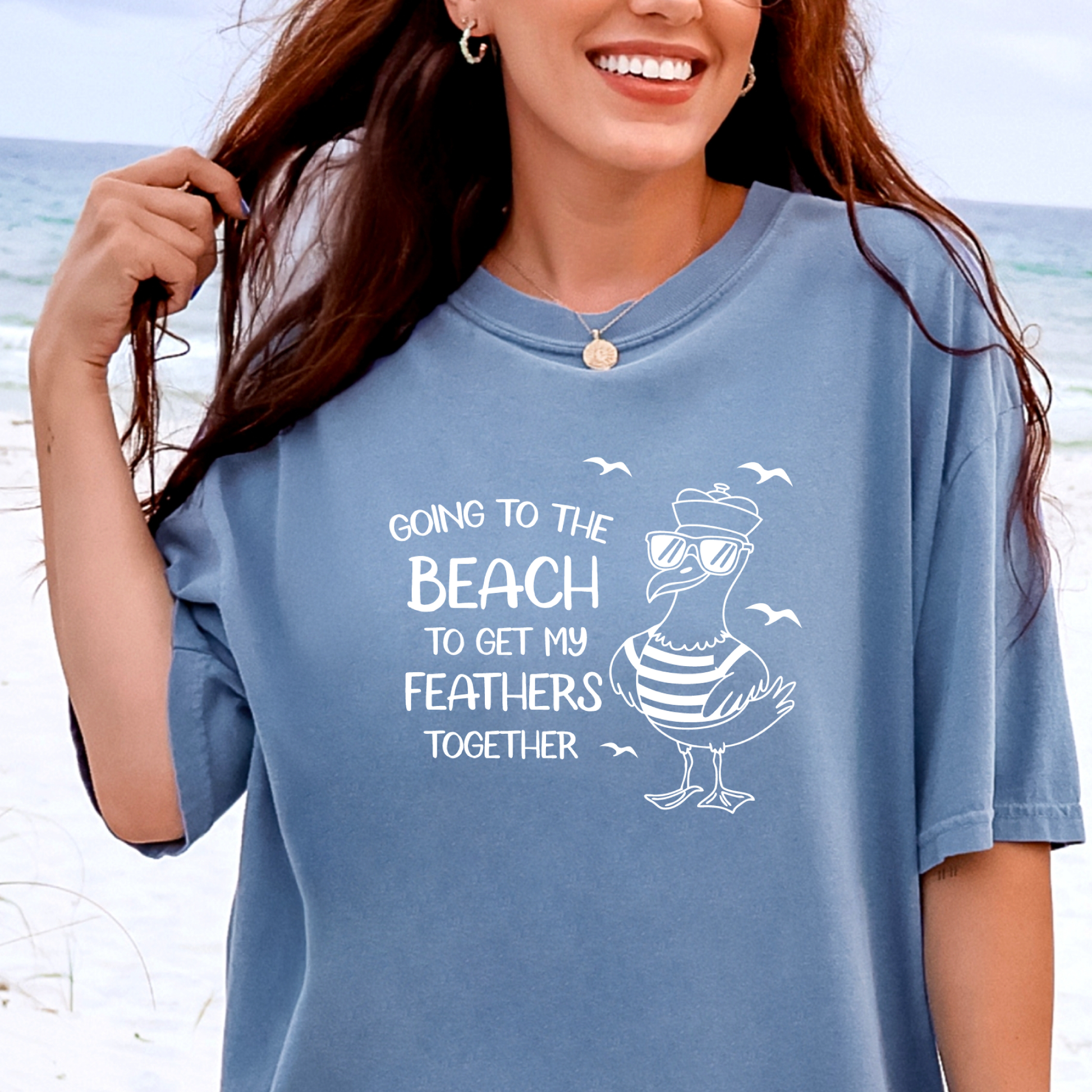 Comfort Colors t-shirt featuring a humorous blue seagull graphic wearing sunglasses and a striped shirt, beside the text “Going to the Beach to Get My Feathers Together.” Several flying birds surround the design, adding a fun coastal feel. This unisex garment-dyed tee offers a soft, vintage texture and relaxed fit, perfect for beach lovers, ocean fans, and anyone who enjoys playful summer graphic shirts.
