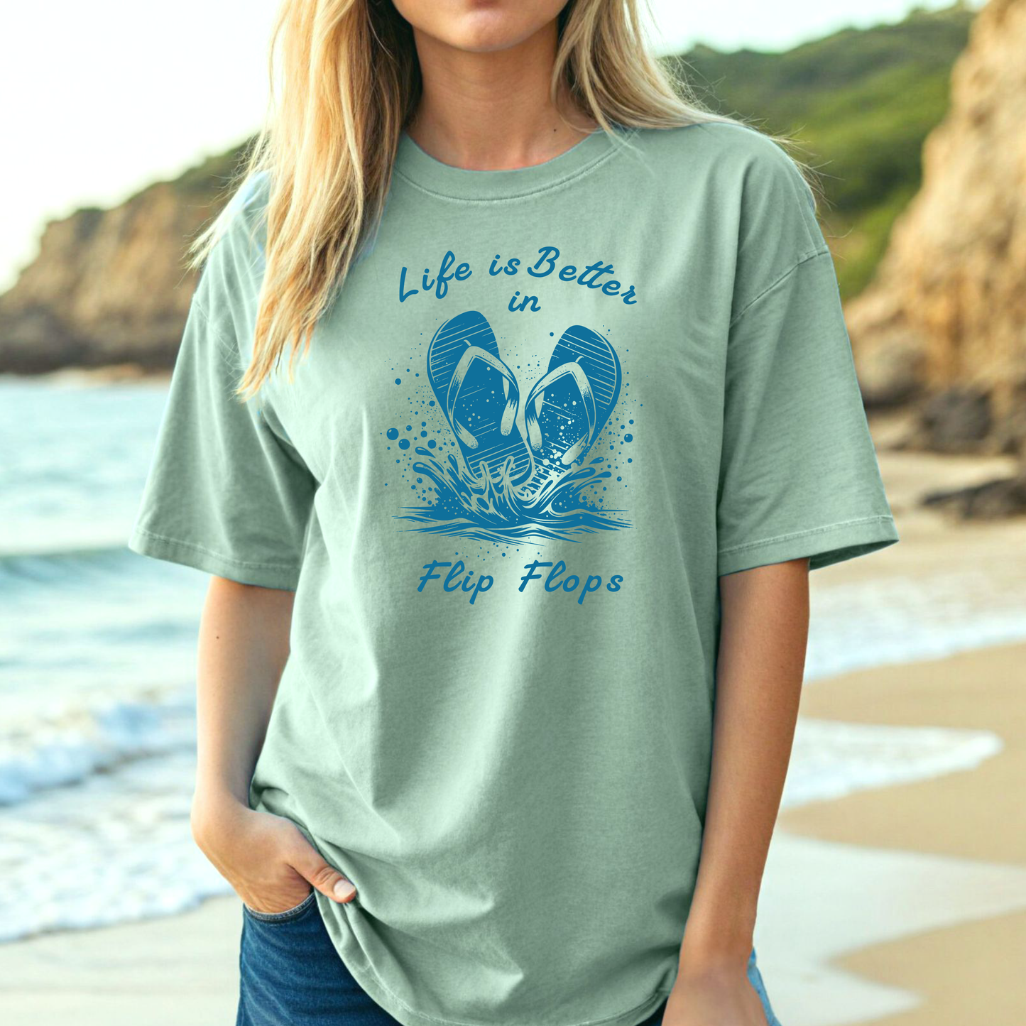 Comfort Colors 1717 "Life is Better in Flip Flops" t shirt with a pair of flip flops splashing in water one color graphic. Picture of a girl on the beach wearing an oversized t shirt.