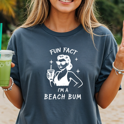 Person wearing a t-shirt with a beach-themed graphic and text on a beach.