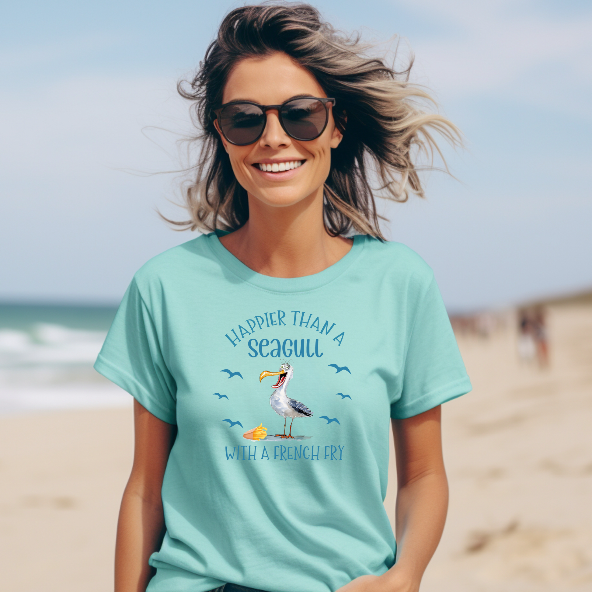 Bella and Canvas 3001 "Happier Than A Seagull With A French Fry" t shirt with an illustration of a seagull with a box of French fries and seagulls flying in the air. Picture of a girl standing on the beach wearing a t shirt.