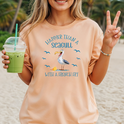 Woman on a beach wearing a peach t-shirt with a seagull graphic and text, holding a drink.