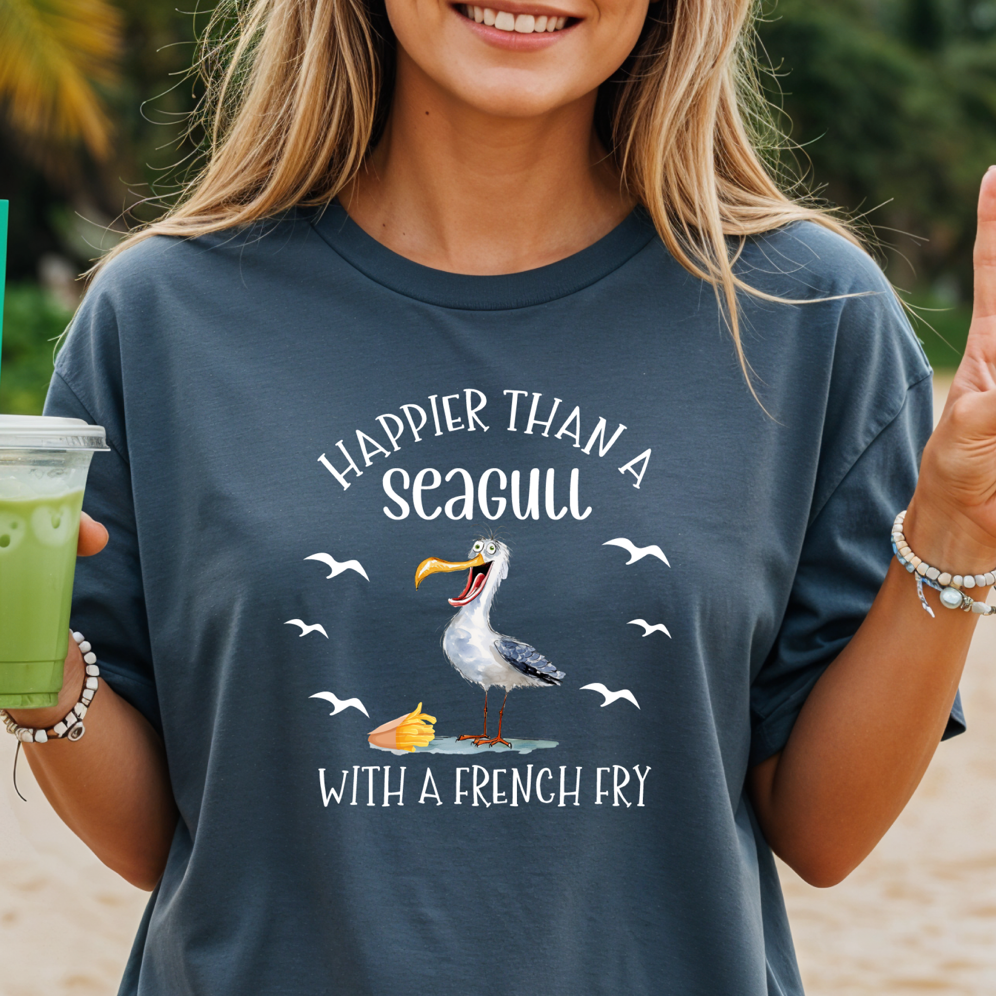 Person wearing a t-shirt with a seagull graphic and text on a beach.