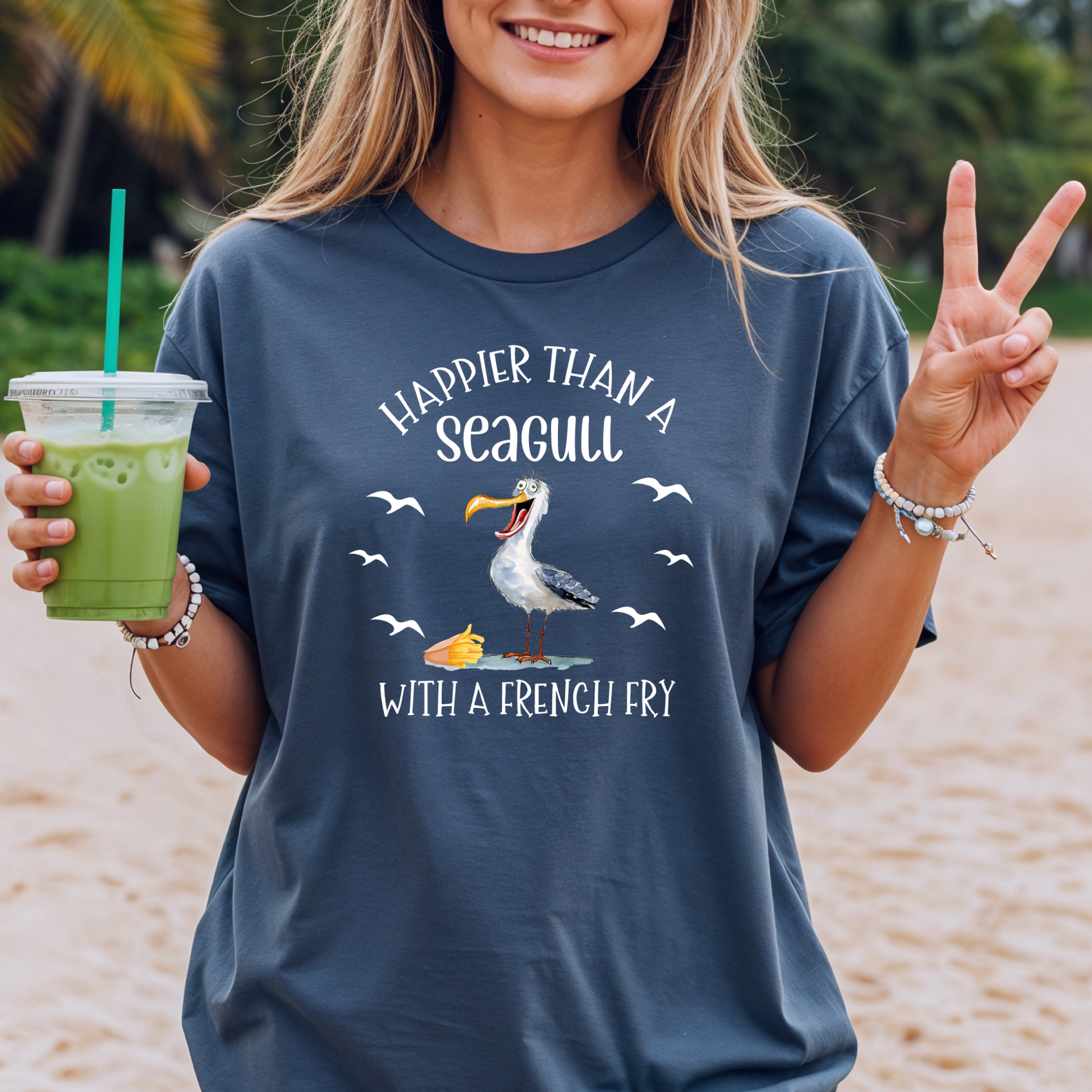 Person wearing a t-shirt with a seagull graphic and text on a beach