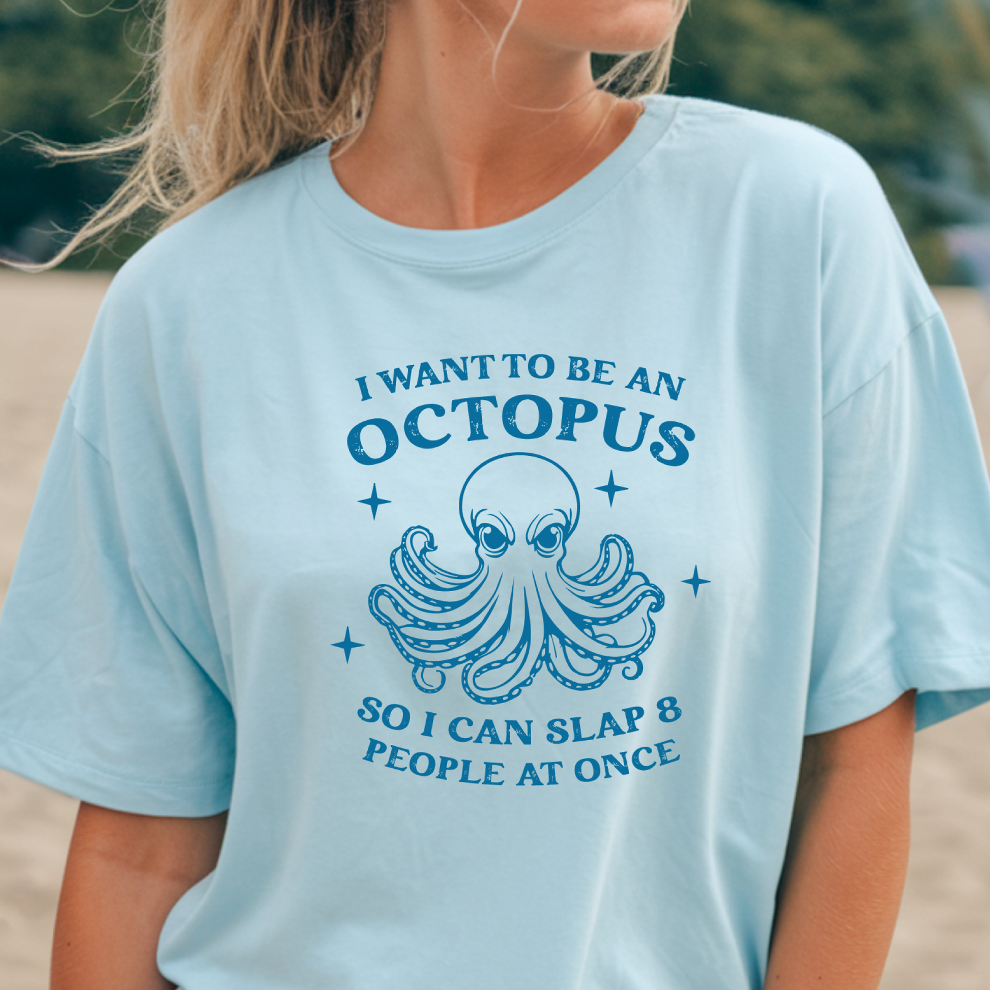 Light blue t-shirt with an octopus graphic and humorous text worn by a person outdoors.