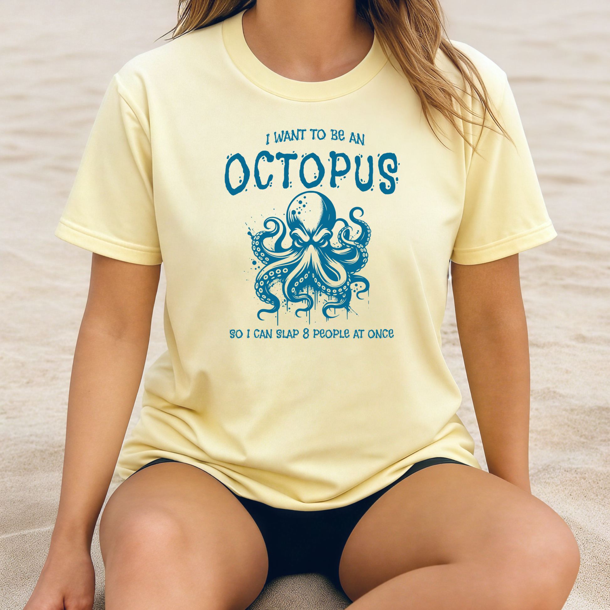 Comfort Colors 1717 "I Want To Be On Octopus So I Can Slap 8 People At Once" t shirt with an angry octopus one color graphic. Picture of a girl sitting on the beach in an oversized t shirt.