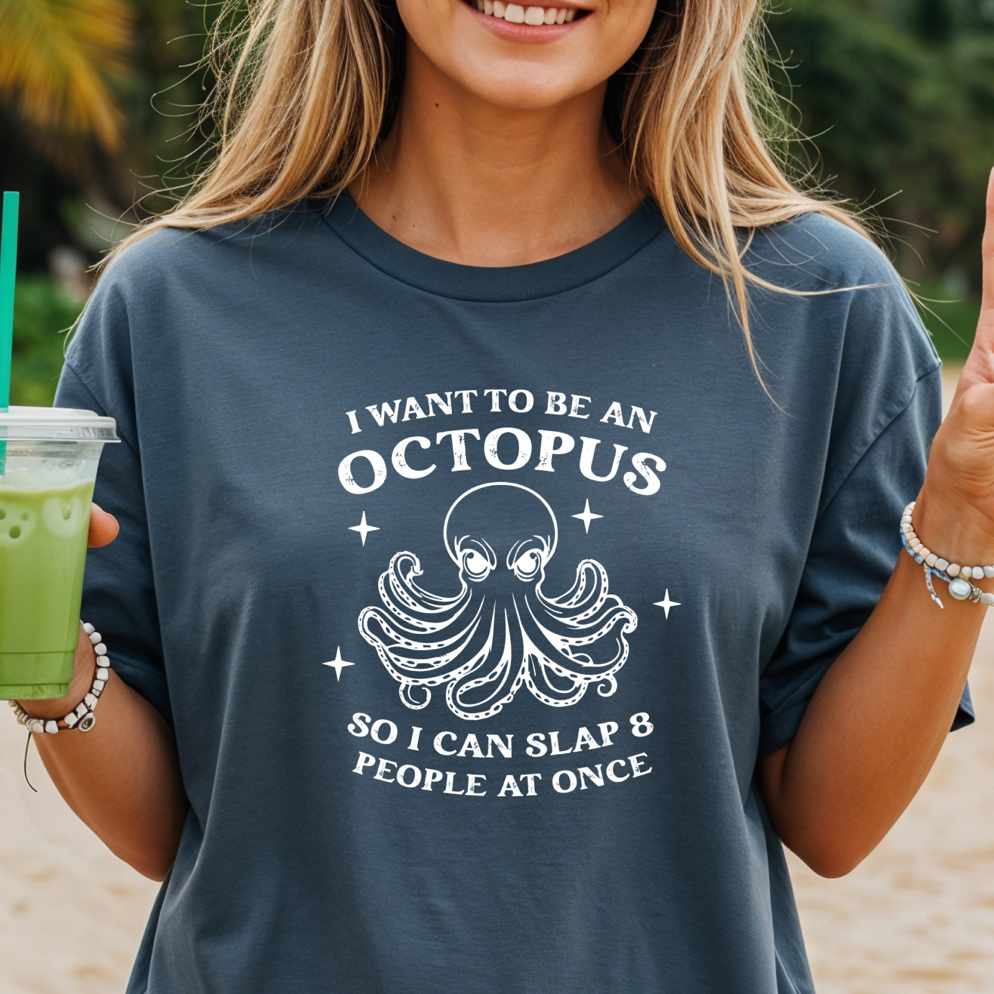 Person wearing a t-shirt with an octopus design and text on a beach.