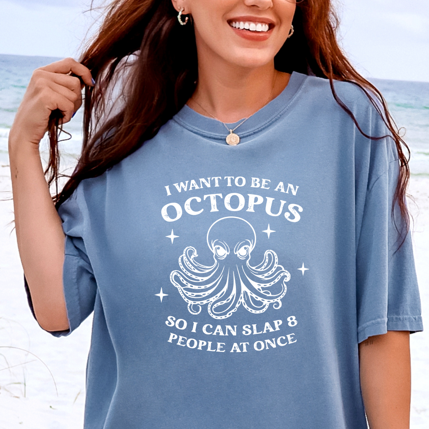 Person wearing a blue jean t-shirt with an octopus graphic and text on a beach.