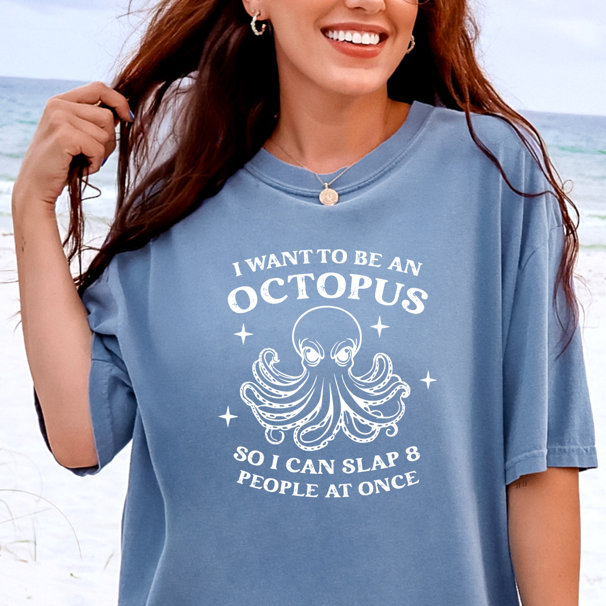 Person wearing a blue jean t-shirt with an octopus graphic and text on a beach.