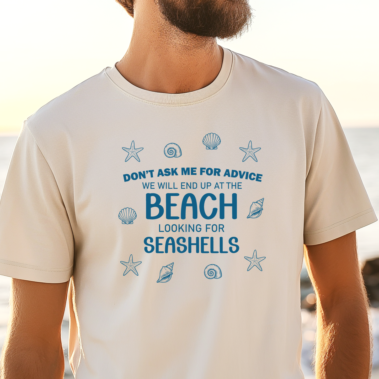 Person wearing a t-shirt with beach-themed text and graphics at a beach.