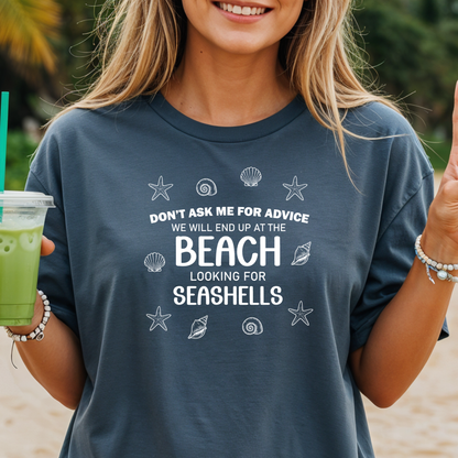Person wearing a t-shirt with a beach-themed quote, holding a drink on a beach.