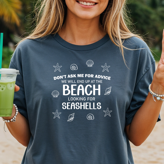 Person wearing a t-shirt with a beach-themed quote, holding a drink on a beach.