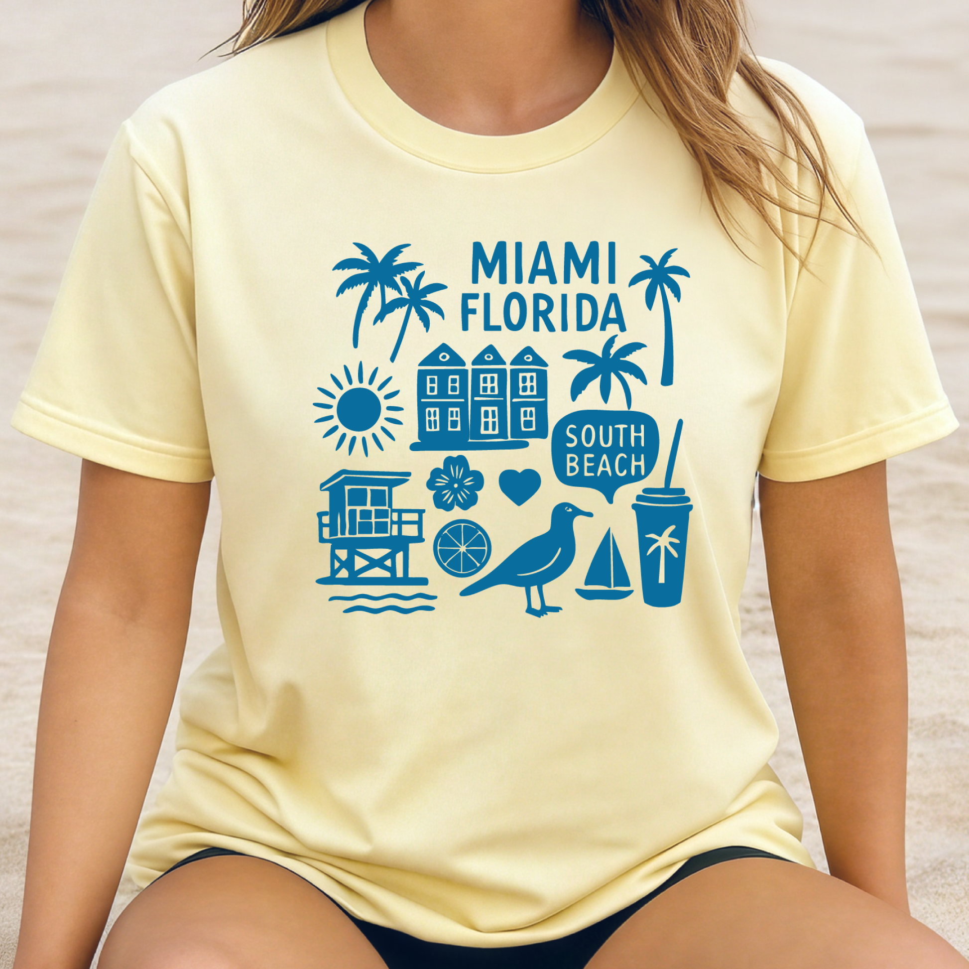 Person wearing a yellow t-shirt with blue Miami Florida graphics on a beach.