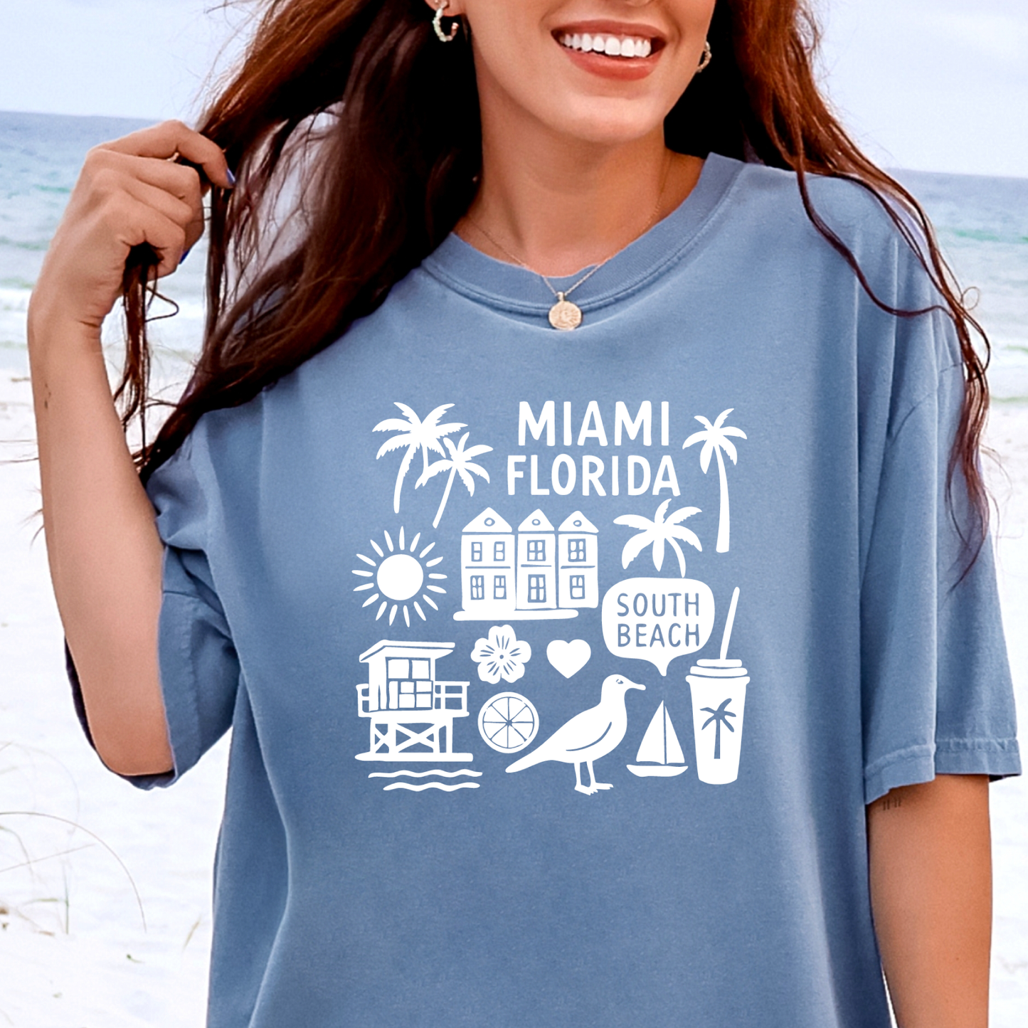 Woman wearing a blue t-shirt with Miami Florida graphics on a beach.