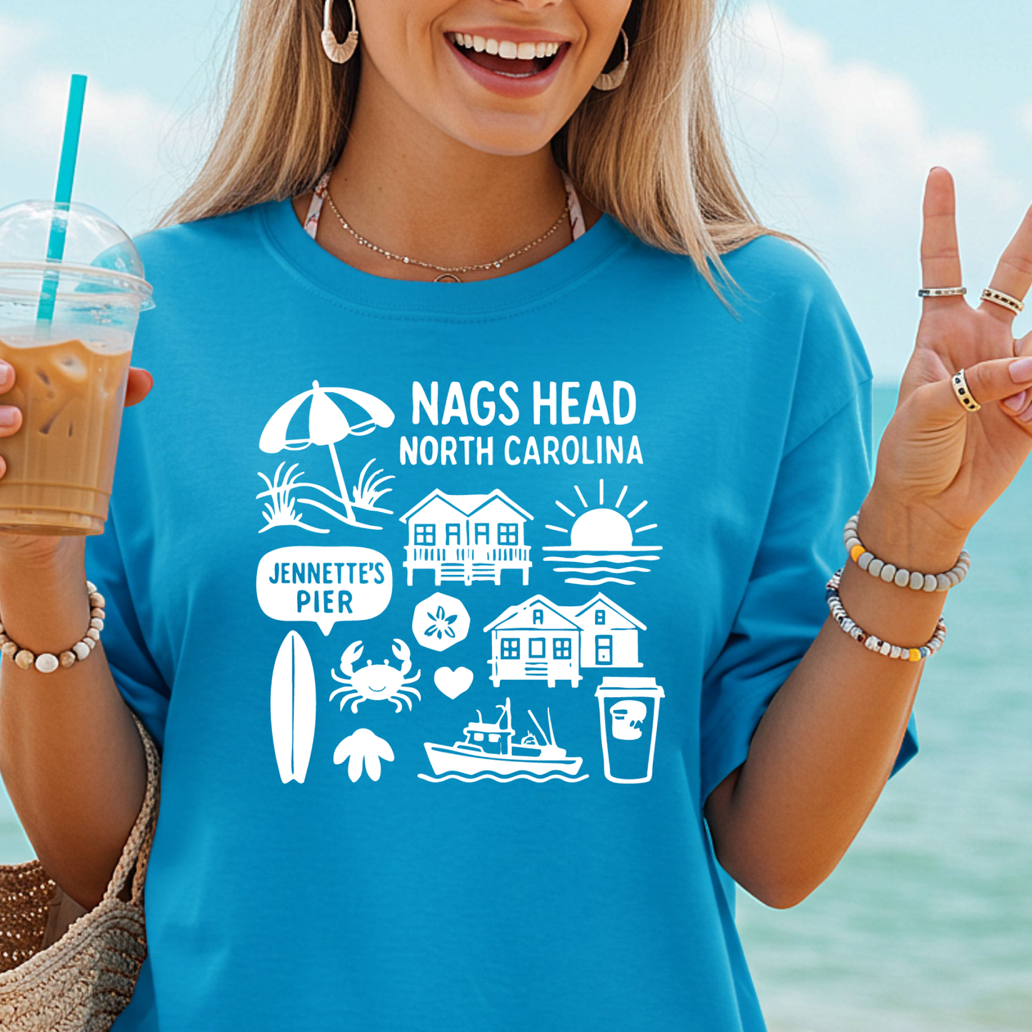 Woman wearing a blue t-shirt with Nags Head, North Carolina design by the ocean.