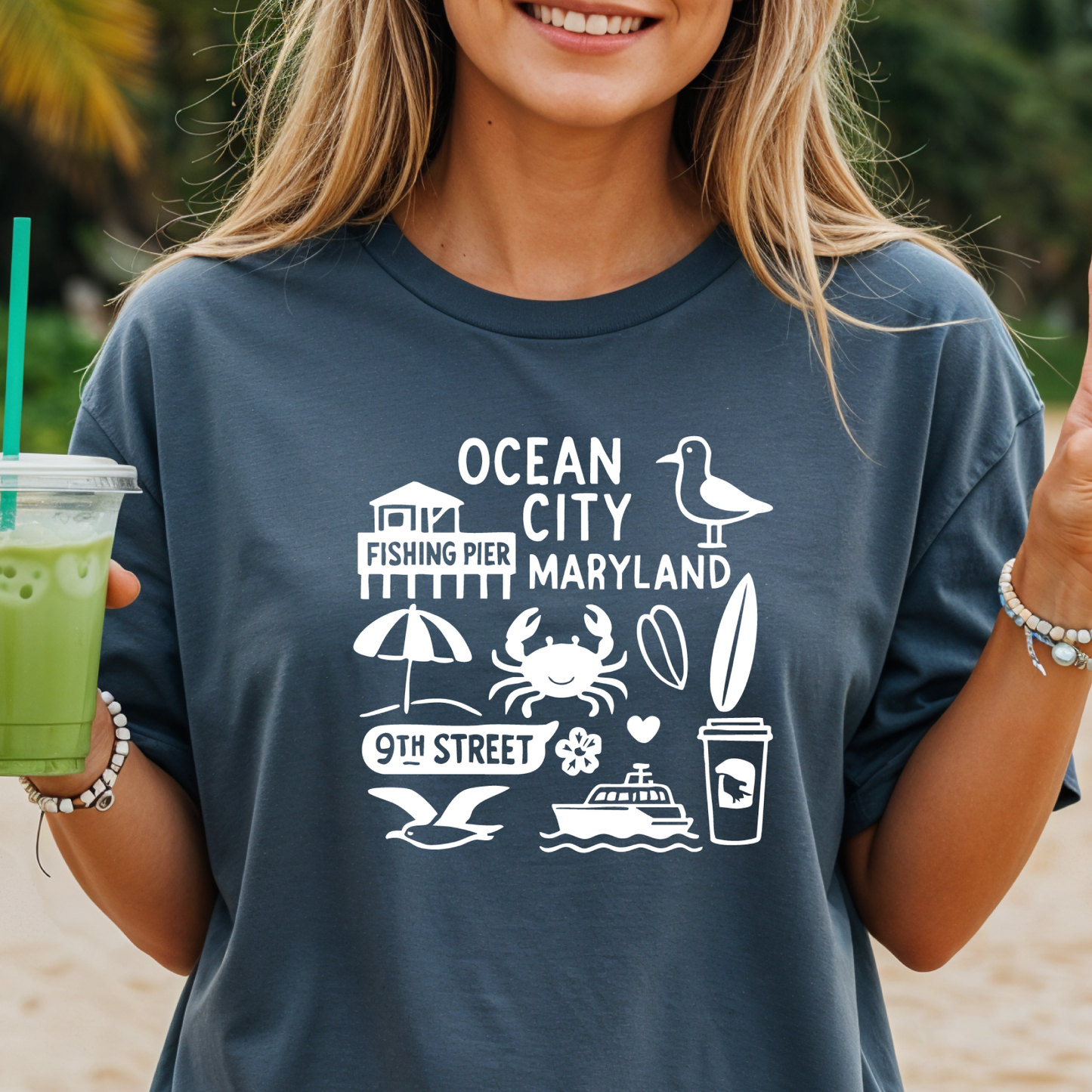 Person wearing a t-shirt with Ocean City, Maryland graphics on a beach.