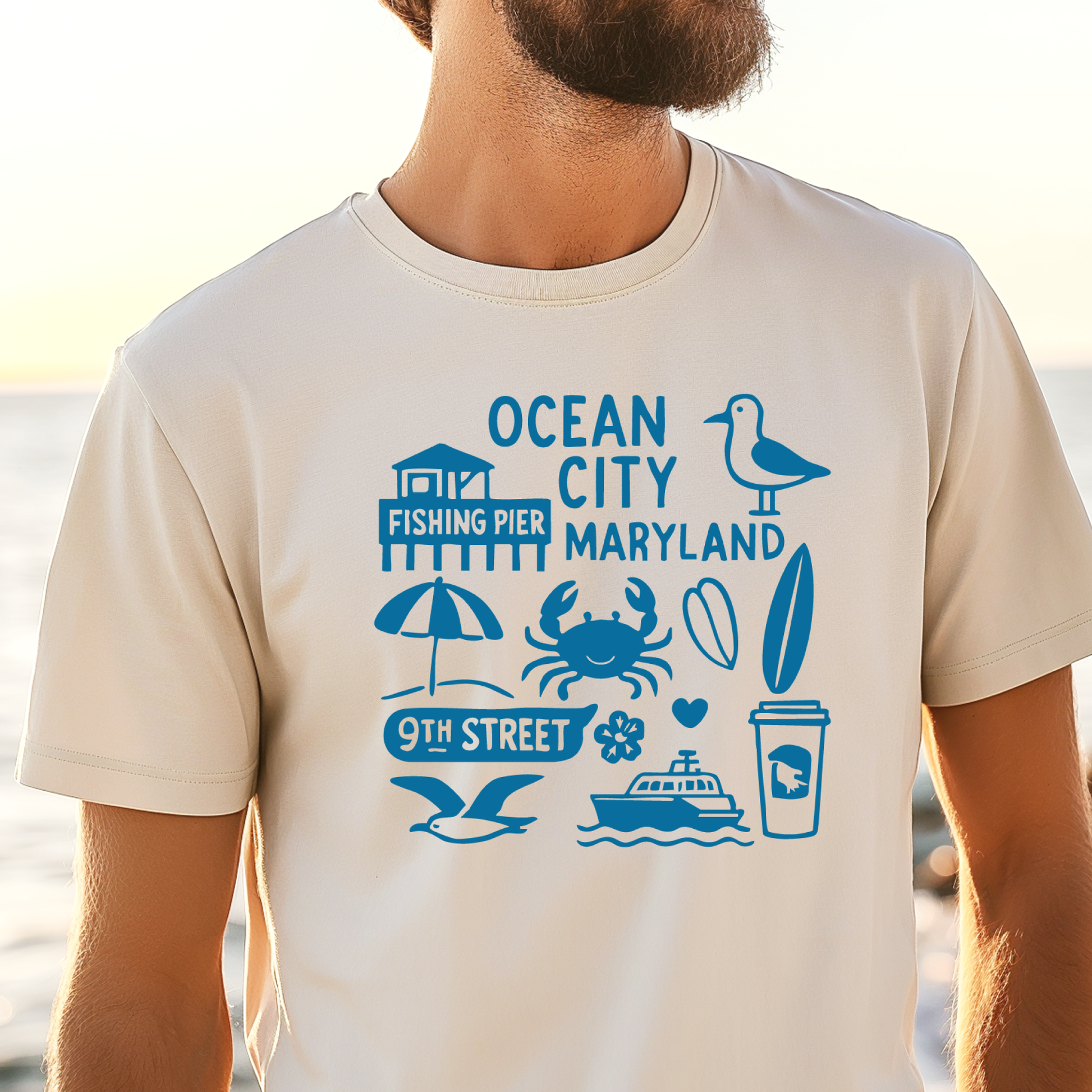 Person wearing a t-shirt with blue graphics and text on a beach.