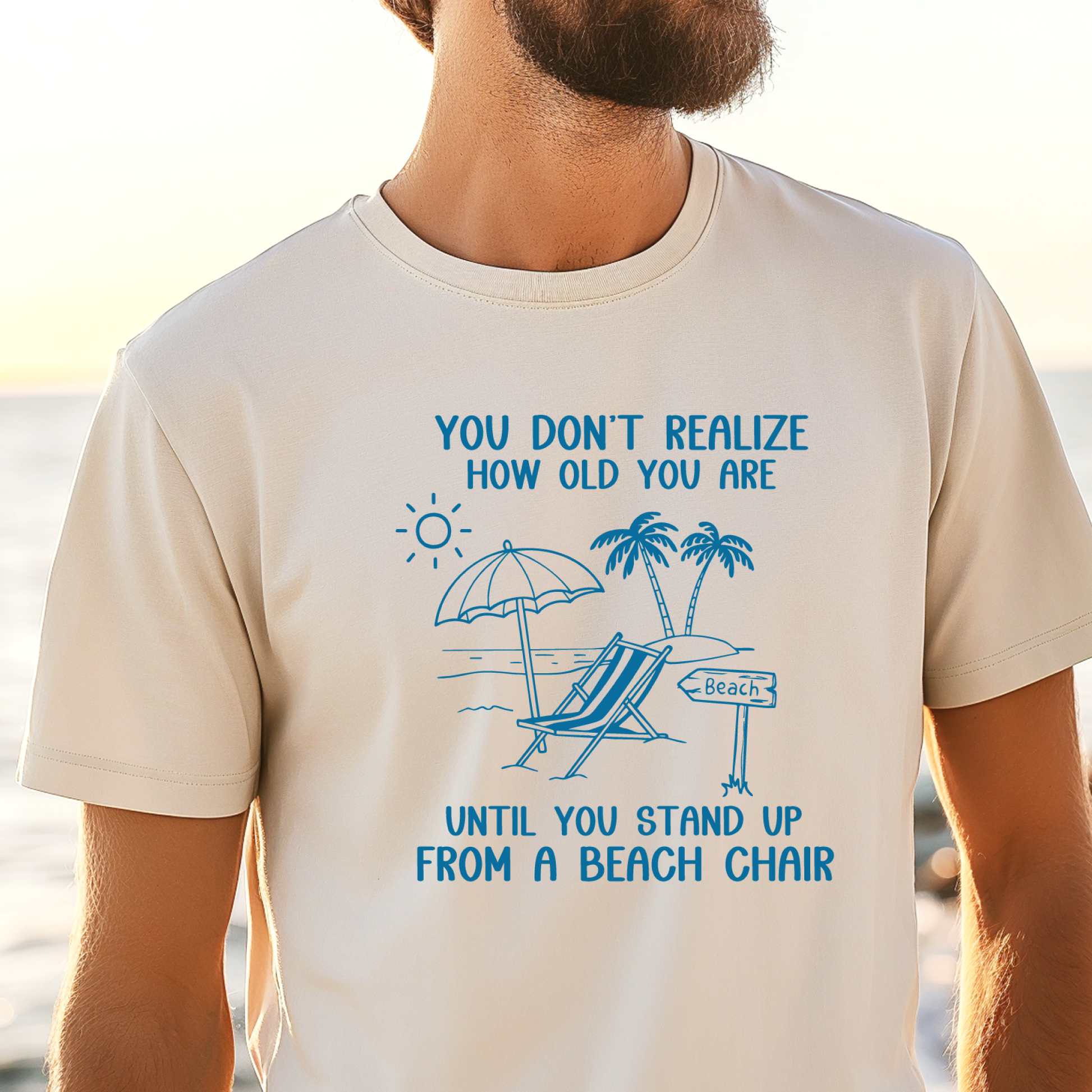 Beige t-shirt with blue graphic and text on a beach background