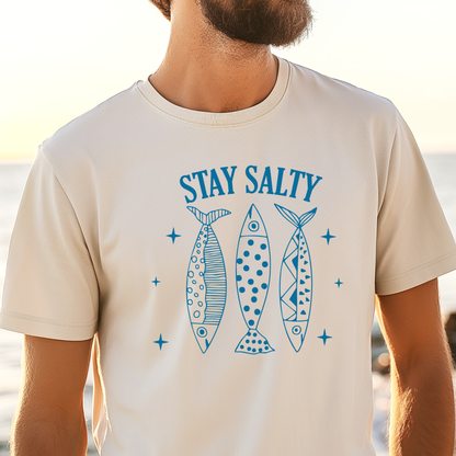 Person wearing a t-shirt with 'Stay Salty' and fish graphics at the beach.