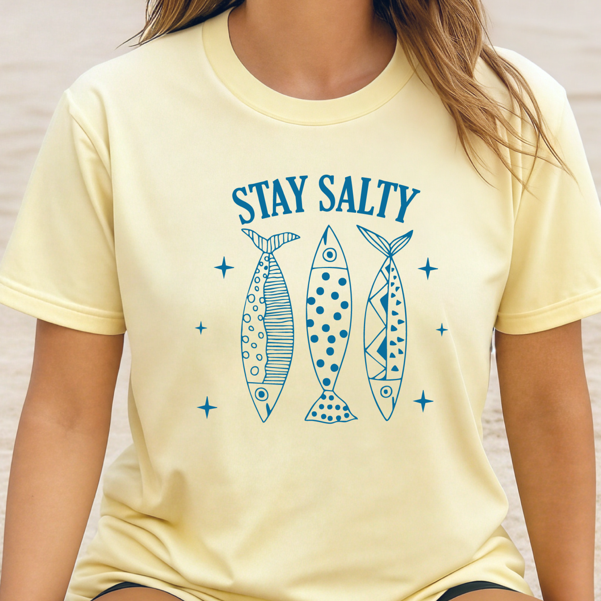 Person wearing a yellow t-shirt with 'Stay Salty' text and fish illustrations.