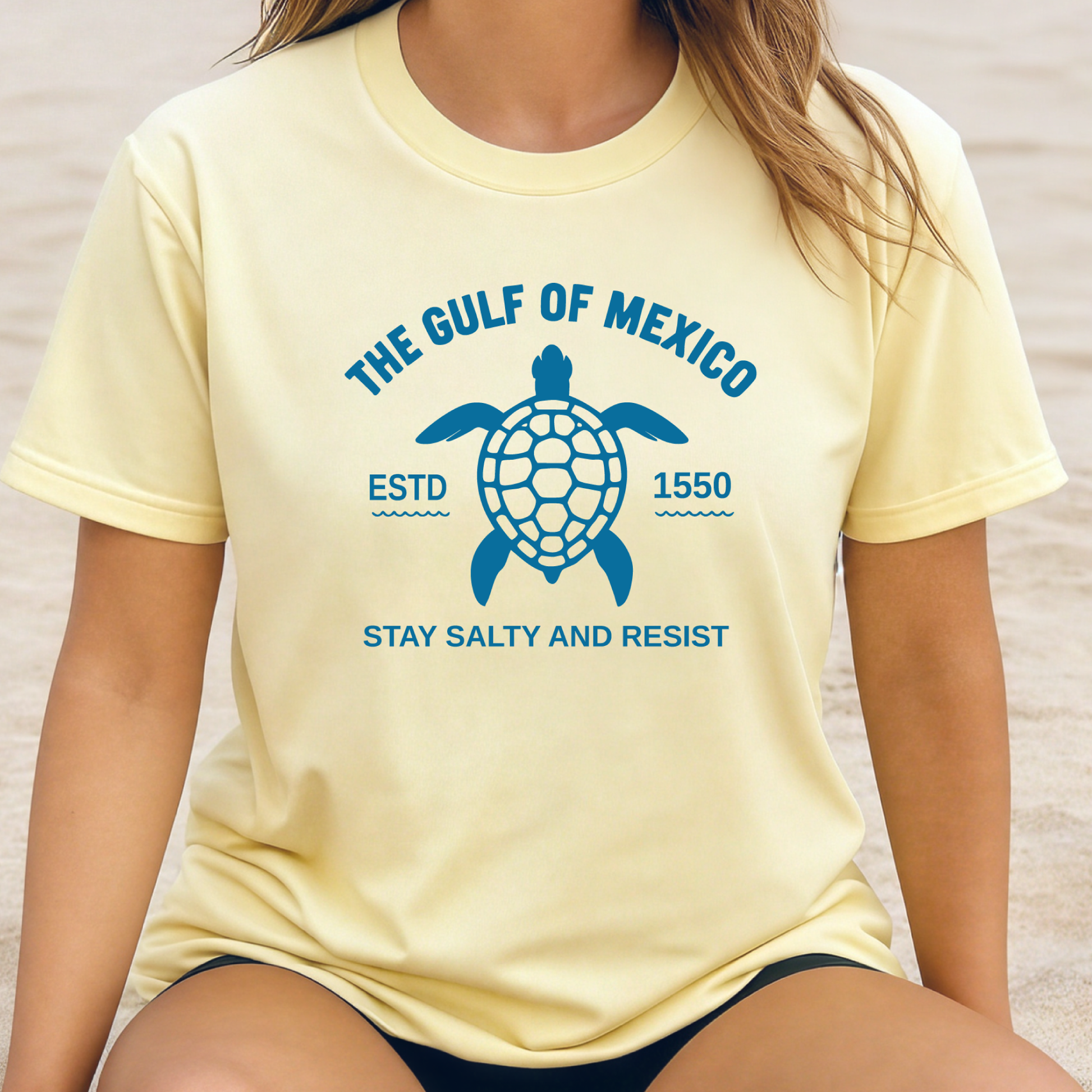 Person wearing a yellow t-shirt with a turtle graphic and text about the Gulf of Mexico.