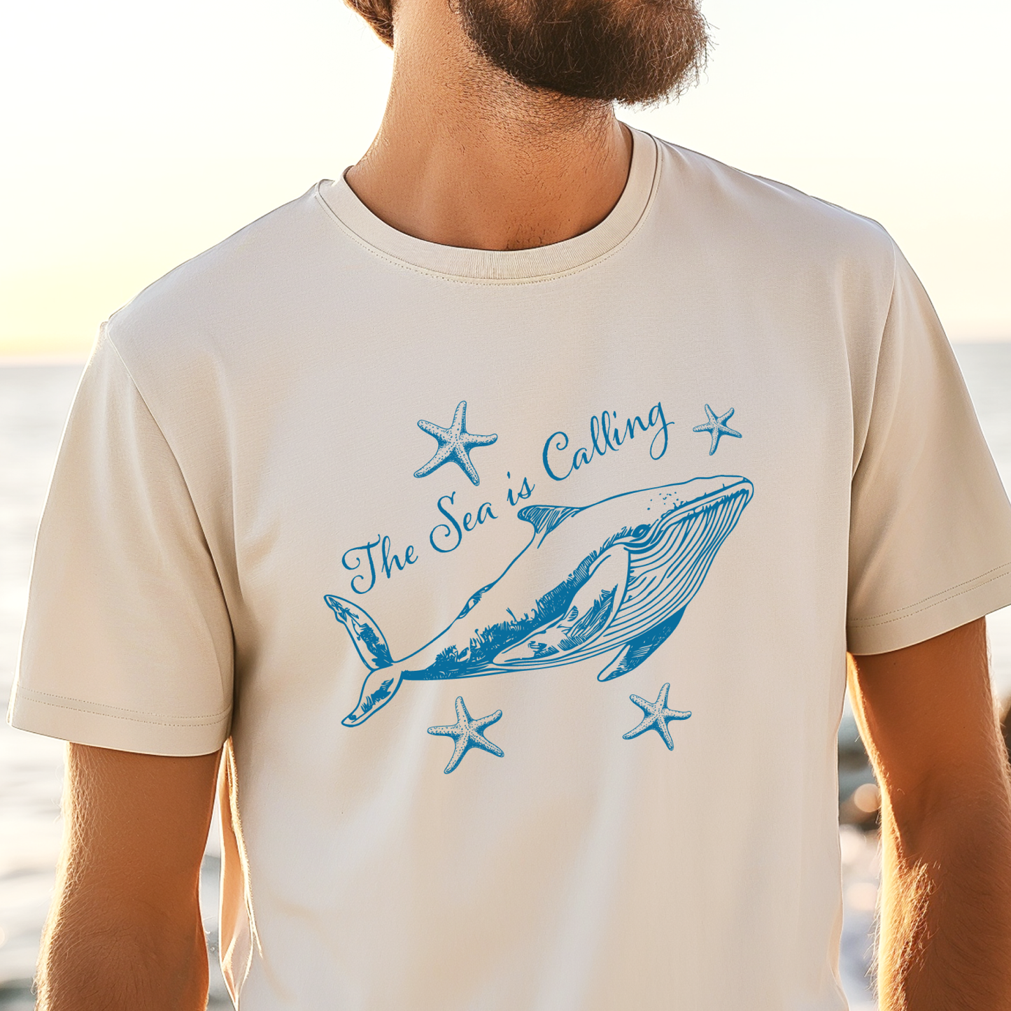 Comfort Colors t-shirt featuring a blue whale illustration surrounded by starfish and the handwritten-style text “The Sea is Calling.” The detailed marine artwork creates a calming coastal aesthetic. This unisex garment-dyed tee offers a soft vintage feel and relaxed fit, perfect for ocean lovers, beach trips, and anyone who enjoys sea-themed graphic shirts with a coastal vibe.
