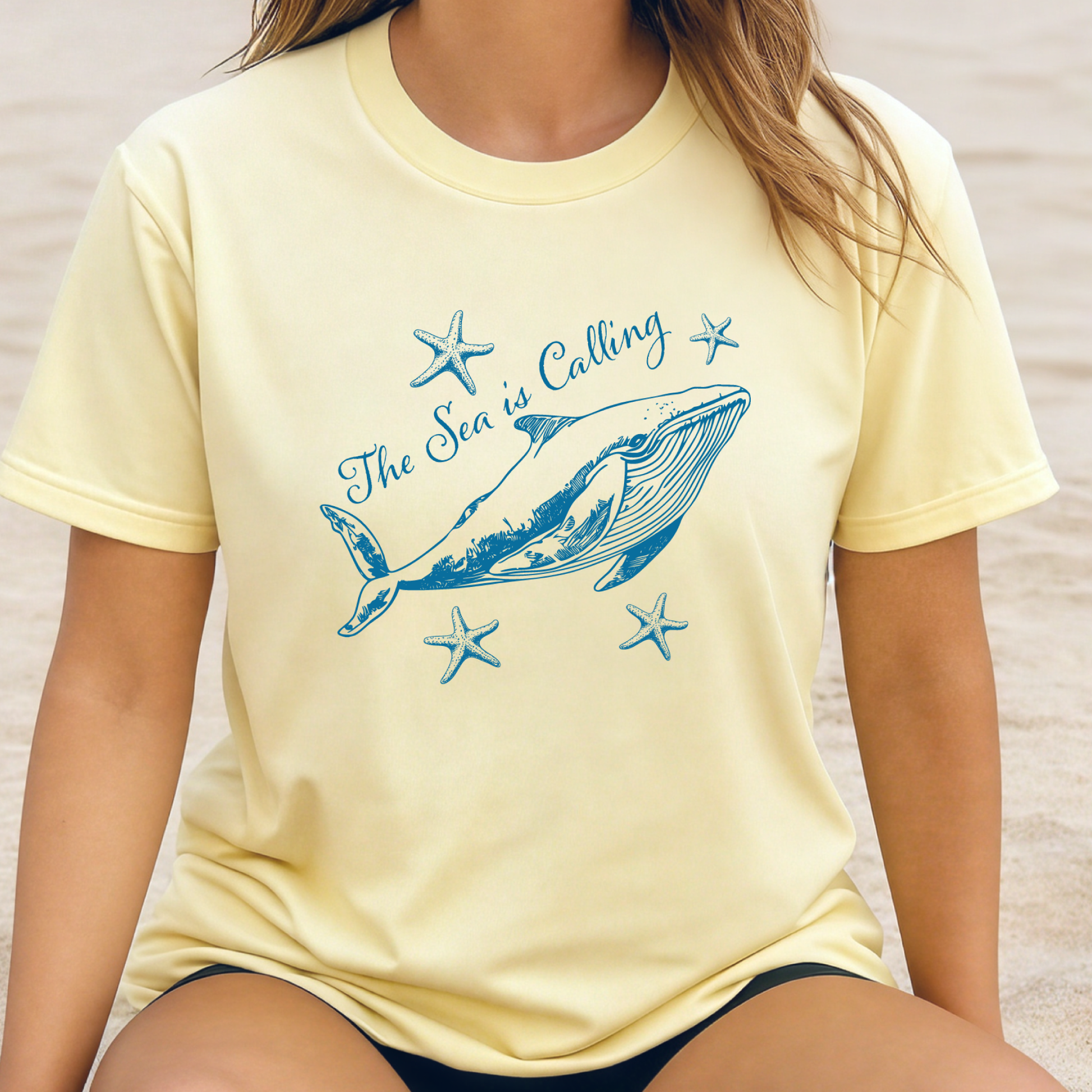 Comfort Colors t-shirt featuring a blue whale illustration surrounded by starfish and the handwritten-style text “The Sea is Calling.” The detailed marine artwork creates a calming coastal aesthetic. This unisex garment-dyed tee offers a soft vintage feel and relaxed fit, perfect for ocean lovers, beach trips, and anyone who enjoys sea-themed graphic shirts with a coastal vibe.