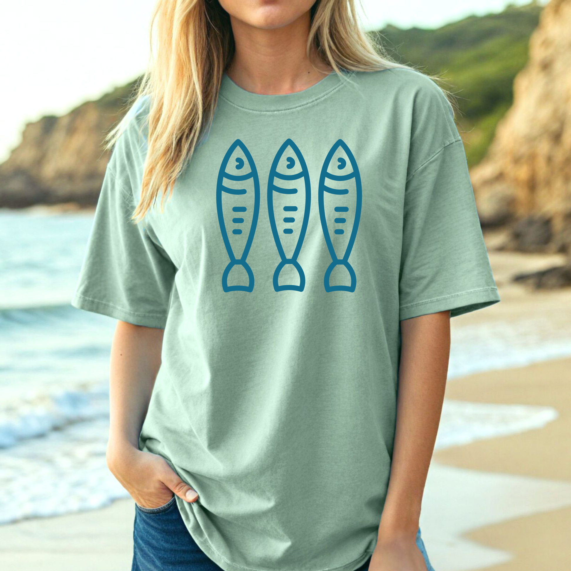 Comfort Colors 1717 Fisherman's Aesthetic t shirt with three sardines in a  one color graphic. Picture of a girl on the beach in an oversized t shirt.