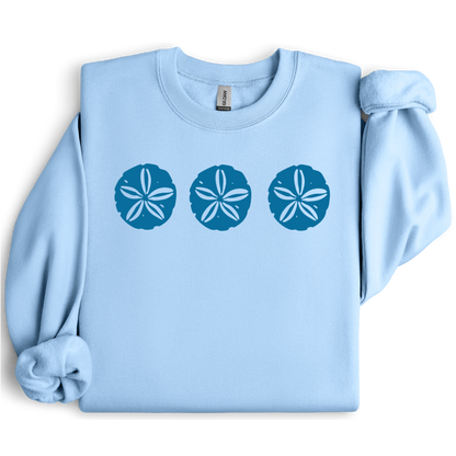 Gildan sweatshirt featuring three blue sand dollar graphics printed across the chest. Soft cotton-poly blend fabric with ribbed cuffs and waistband for a cozy, durable fit. Perfect for beach lovers and coastal style enthusiasts who appreciate simple ocean-inspired designs. Ideal for layering on cool seaside evenings or adding a subtle beach vibe to casual outfits.