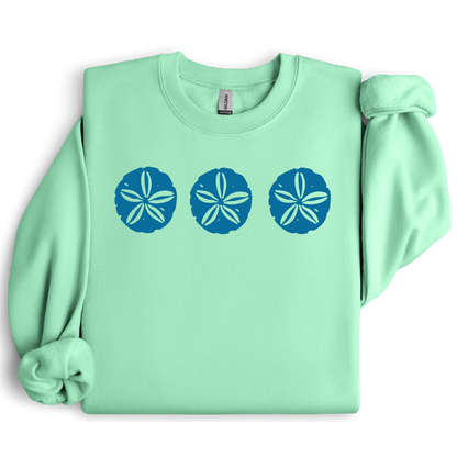 Gildan sweatshirt featuring three blue sand dollar graphics printed across the chest. Soft cotton-poly blend fabric with ribbed cuffs and waistband for a cozy, durable fit. Perfect for beach lovers and coastal style enthusiasts who appreciate simple ocean-inspired designs. Ideal for layering on cool seaside evenings or adding a subtle beach vibe to casual outfits.