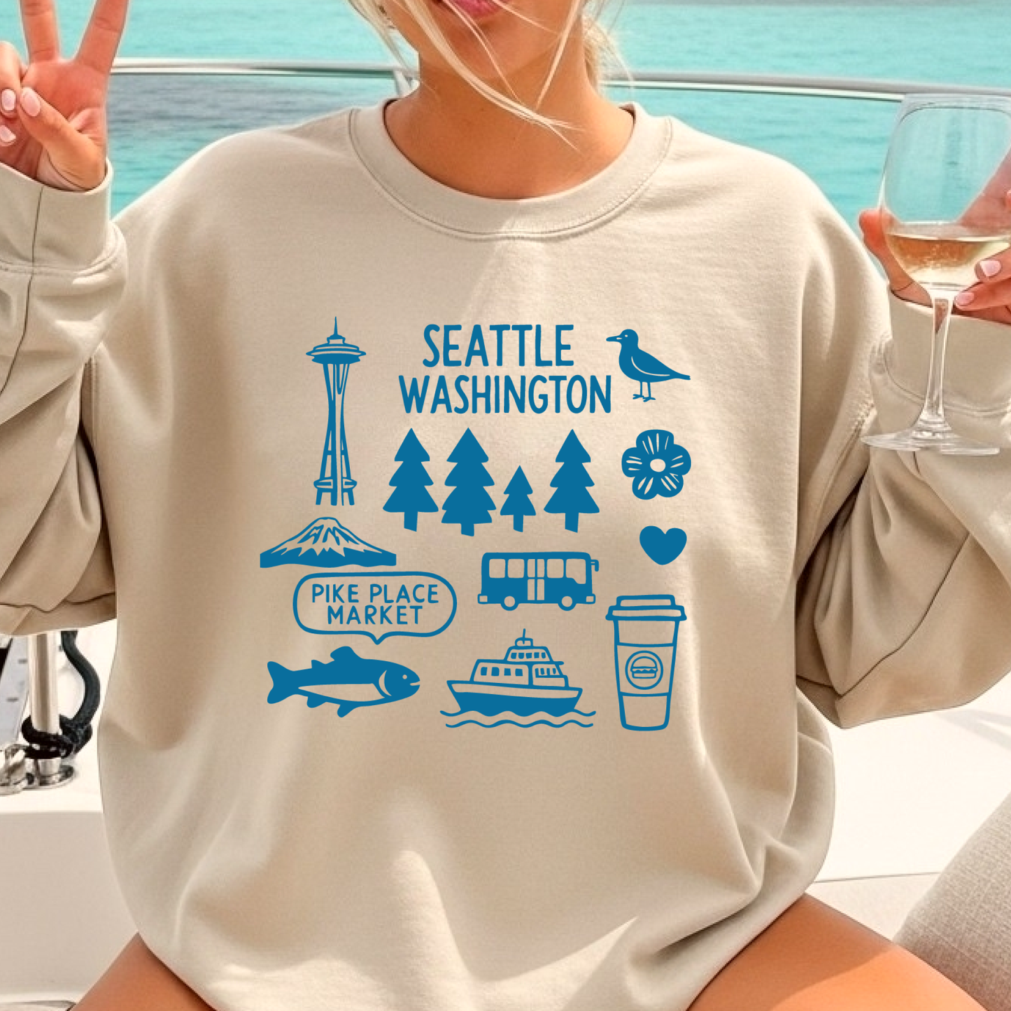 Person wearing a beige sweatshirt with blue Seattle-themed graphics on a boat.