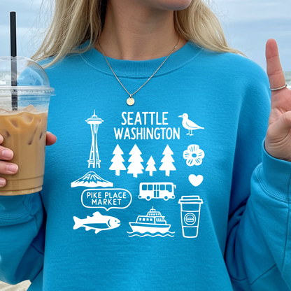 Person wearing a blue sweatshirt with Seattle-themed graphics, holding a drink.