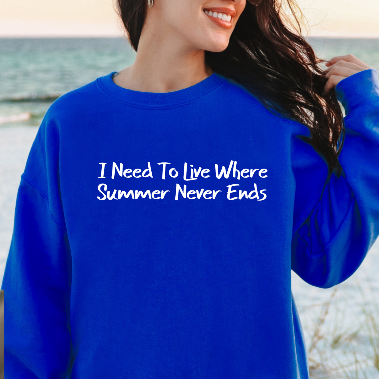 Gildan sweatshirt featuring blue text that reads “I Need To Live Where Summer Never Ends.” Cozy beach-inspired pullover for those who love the sun and ocean lifestyle. Made with a soft cotton-poly blend, ribbed cuffs, and double-needle stitching for durability. Perfect for coastal adventures, vacations, or casual summer-style outfits. Ideal gift for beach lovers and anyone who wishes for endless summer days.