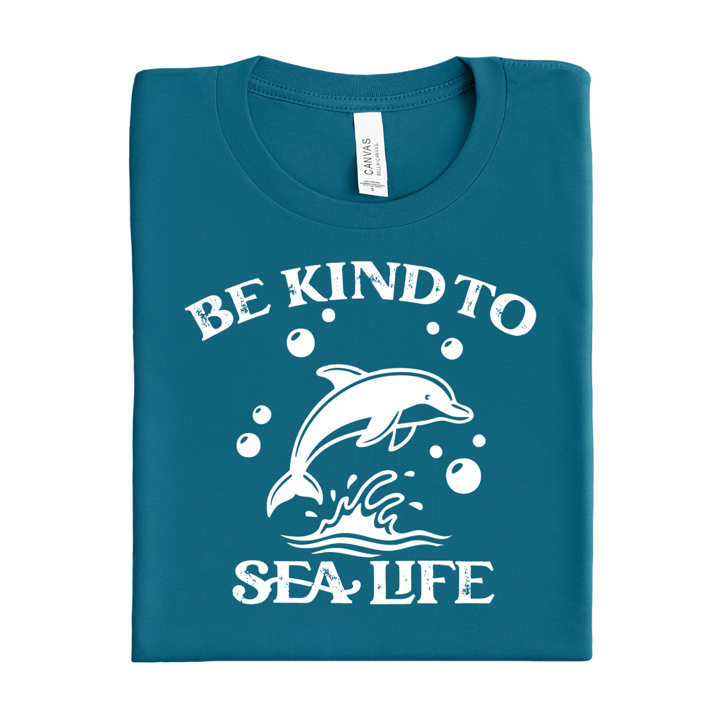 Folded deep teal t-shirt with white dolphin graphic and text 'Be Kind to Sea Life' on a white background